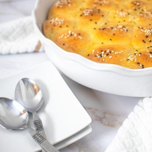 A pan of cream cheese rolls with some serving-ware next to it.