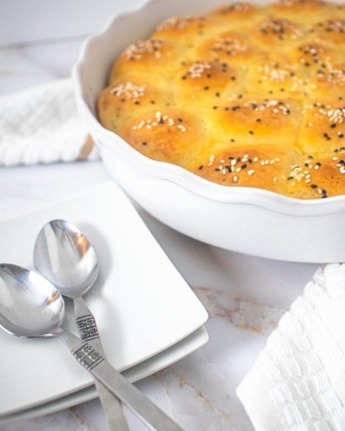 A pan of cream cheese rolls with some serving-ware next to it.