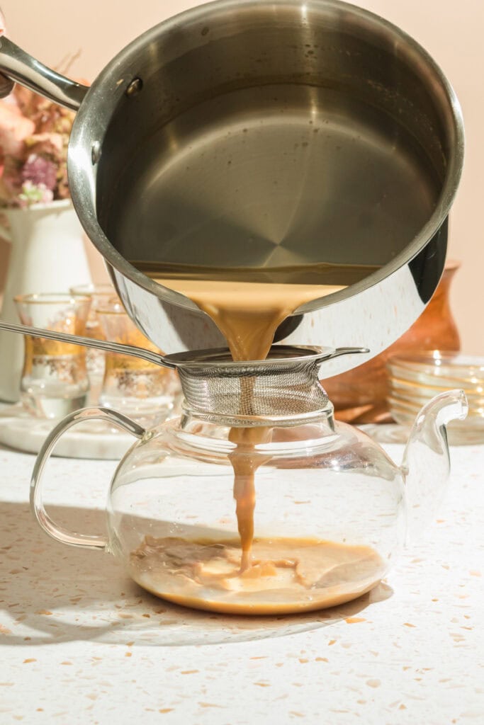 Pouring somali tea into a glass tea pot from a pot