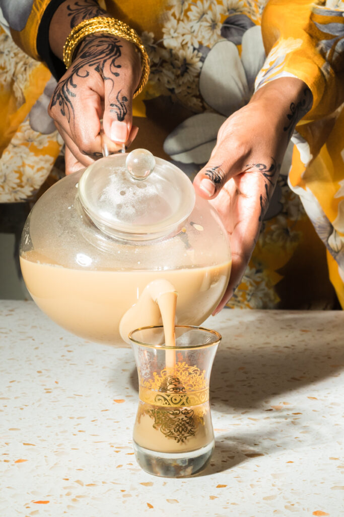 woman wearing traditional somali dress pouring tea into a glass cup