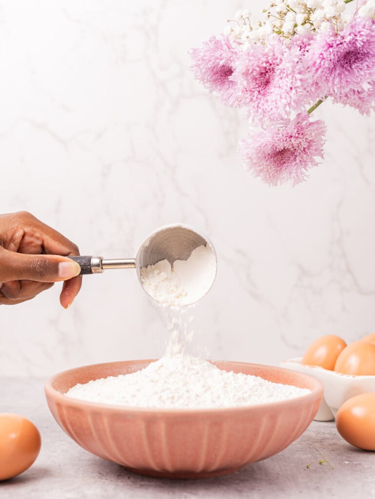 pouring sugar into a pink bowl
