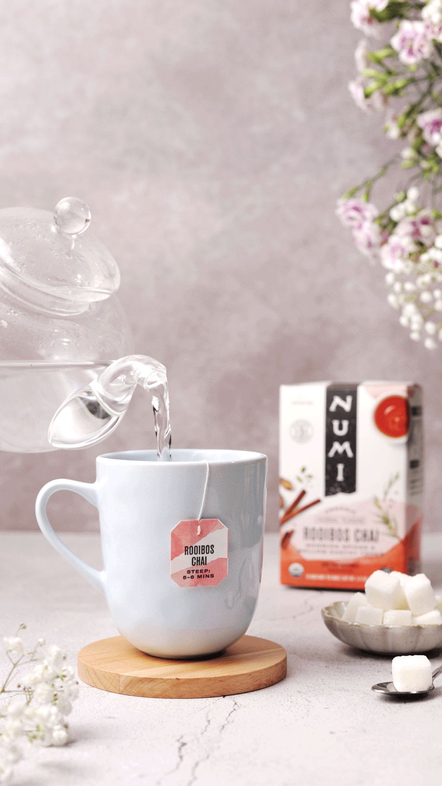 a glass tea kettle pouring hot water into a mug